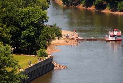 [A floating dock leads to the boat in the deeper, middle part of the river. Trees line either side of the river.]